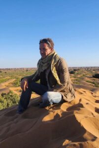Abdel Anik assis sur une dune dans le désert